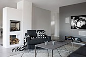 Grey-painted lounge area with delicate coffee table, black armchair and masonry fireplace