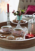 A Christmas tea break – tea cups and bowls of nuts next to a candle holder with a burning candle