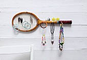 Old tennis racquet mounted on wall as jewellery rack