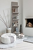 Pouffe and balls of wool in basket on animal-skin rug in front of open fireplace