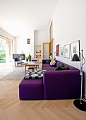 Light-flooded living room with purple sofa and retro standard lamp on herringbone floor