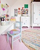 Shabby-chic chair at white desk, rustic half-height cabinet next to wardrobe on wooden floor painted pink