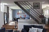 Elegant, open-plan living area with steel staircase and oak flooring in harmonious blend of grey and blue shades