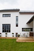 Modernes Wohnhaus mit rustikaler Holzterrasse und grünem Rasen