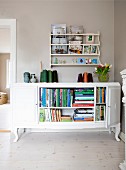 Old dresser used as bookcase below shelving unit on grey-painted wall