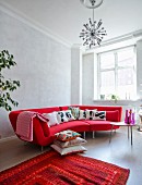 Bright red designer sofa with black and white scatter cushions in renovated town-house apartment with retro ambiance