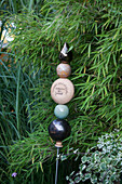 Garden ornament made from baubles on metal rod in front of bamboo bush