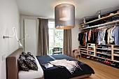 Upholstered bed, modern lamps and open-fronted wardrobe in bedroom