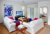 Living room furnished in white with bold accents of magenta and royal blue