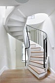 White-painted spiral staircase with wooden treads and black metal balustrade