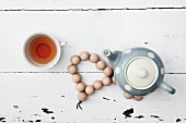 Retro teapot on hand-crafted coaster of wooden beads and cup of tea