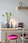 Stool with deep pink cushion and chair in front of rustic desk
