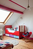 Kinderzimmer unter dem Dach, Klassiker Schaukelstuhl mit roter Sitzschale neben Schlittenbett in Rot