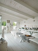 Minimalist, modern lake house with interior painted entirely white; set table with sheepskin blankets on wooden bench