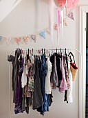 White clothes rail holding girl's clothing and pastel bunting hung on wall