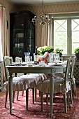 Antique dining table an chairs with ruffled cushions in rustic dining room