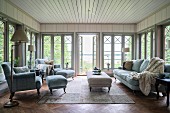 Pale grey armchair, footstool and coffee table in rustic living room with floor-to-ceiling lattice windows