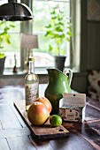 Fruit on wooden board and retro jug on table in front of window