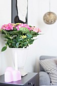 White vase of pink hydrangeas on side table