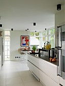 Open-plan kitchen with modern counter and dining area flanked by French doors in background