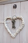 Heart-shaped wreath of white-painted straw and bunch of vintage keys on hook
