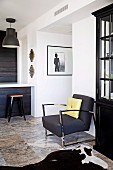 Elegant retro armchair with chrome steel frame and black industrial lamps above kitchen counter with vintage-style stool