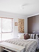 Schlafzimmer mit gesticktem Wandbehang, Vintage Kleiderbank und moderner dunkelbraun getönter Wand