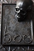 Skull and lettering reading 'boo' made from noodles on metal tray