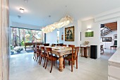 Rustic wooden table and traditional chairs below long lamp with draped lampshade in dining area