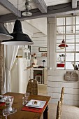 Wooden dining table below pendant lamp in front of kitchen partition with glazed lattice