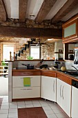 L-shaped kitchen worksurface with raised dining counter in front of staircase in interior with stone walls