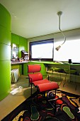 Red designer couch in office with green fitted furnishing and black patterned rug
