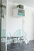 Turquoise retro cord chairs on grey-tiled floor below shelving module on wall