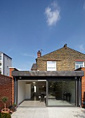 One-storey, modern extension in back yard of traditional, British brick house