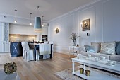 Elegant living-dining room in shades of pale blue and cream with open-plan fitted kitchen in background