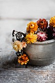 Various dried flowers in stoneware pot on wooden surface