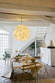 Rustic, whitewashed wooden ceiling with large, floral paper lampshade above table set for Christmas meal