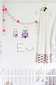 Animal wall stickers and colourful garland next to dress on clothes hanger hung on wall