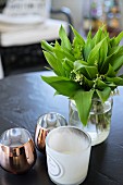 Glass vase of lily of the valley an tealight holders