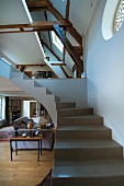 Winding concrete staircase without handrail in interior with converted attic and gallery