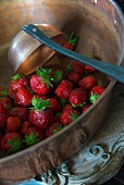 Fresh strawberries and ladle in copper bowl