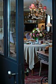 View through half-open door of festively set table and elegant chandelier with pink lampshades