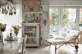 Cushions with white lace covers on bamboo chaise in front of French windows