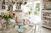 Dining table set with romantic pastel crockery in open-plan shabby-chic kitchen