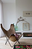 Butterfly chair with pale brown suede cover in front of low sideboard