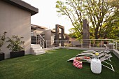 Artificial lawn, sun loungers and drinks on side table on roof terrace