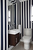 Toilet with compact washstand, bevelled mirror and blue and white striped wallpaper