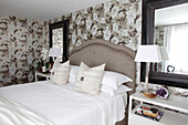 Double bed with curved headboard against floral wallpaper