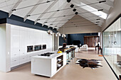 Modern gable roof structure with tension rods above long interior with designer kitchen