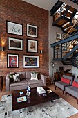 Gallery of pictures on brick wall of loft apartment living room with retro furniture and industrial-style staircase
